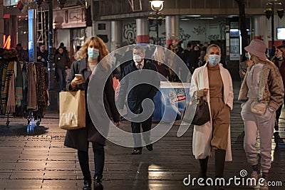 Selective blur on Senior man, white caucasian, walking wearing a facemask on Kneza Mihailova street of Belgrade at night Editorial Stock Photo
