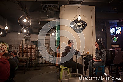 Selective blur on two young adults, man and woman, discussing and drinking in Samo Pivo, a craft beer bar in the city center Editorial Stock Photo