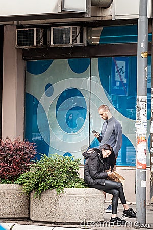 Selective blur on two young persons, man and woman watching their smartphones and looking at its content Editorial Stock Photo