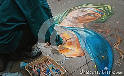 Selective closeup shot of a person painting a female on the ground with oil pencil crayons Editorial Stock Photo