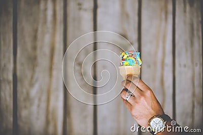 Selective closeup shot of a person wearing a ring and a wristwatch holding a multicolored ice cream Stock Photo