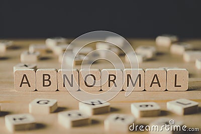 Focus of abnormal lettering on cubes surrounded by blocks with letters on wooden surface isolated on black Stock Photo