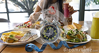 Selective focus of Alarm clock with woman eating a healthy food as Intermittent fasting, time-restricted eating-Diet breakfast Stock Photo