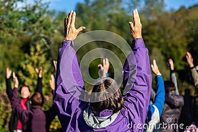 Woman and others practicing yoga outdoors Editorial Stock Photo