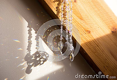 Selective focus on ball and teardrop shape crystal rainbow maker suncatcher hanging in home. Stock Photo