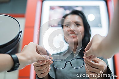 selective focus of a beautiful shop assistant giving a pair of glasses to the customer& x27;s hands Stock Photo