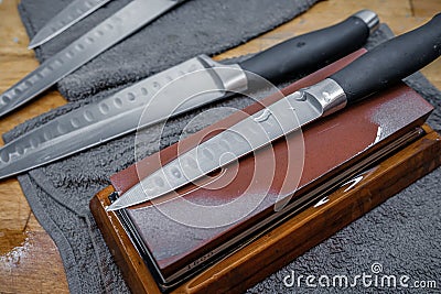 Selective focus on the blade of a steel kitchen knife lying on a water whetstone Stock Photo