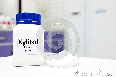 Selective focus of a bottle of pure xylitol sugar substitute with powder in petri dish. White laboratory background Stock Photo