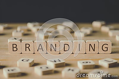 Focus of branding lettering on cubes surrounded by blocks with letters on wooden surface isolated on black Stock Photo