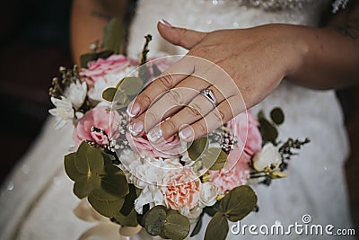 Selective focus of a bride's hands with a promise ring on the background of a bridal bouquet Stock Photo