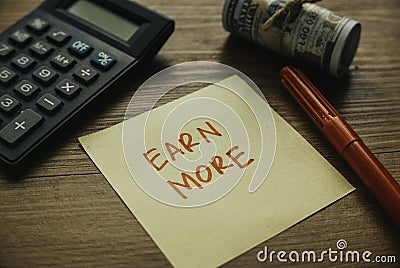 Selective focus of calculator,money pen and paper written with Earn More Stock Photo