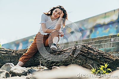 Focus of cheerful woman sitting on tree trunk Stock Photo