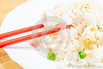 Selective focus closeup of a chopstick on the Chinese fried rice Stock Photo