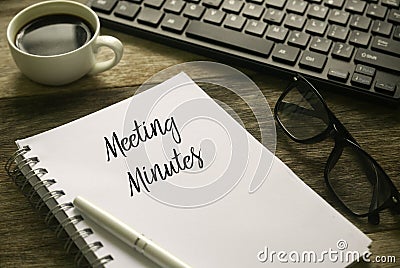 Selective focus of coffee,computer keyboard,glasses,pen and notebook written with Meeting Minutes on wooden background Stock Photo