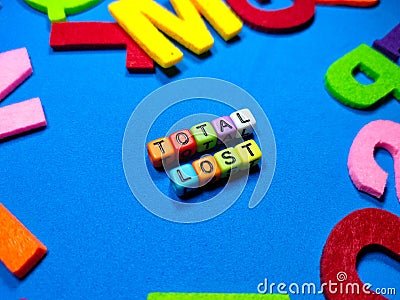 Selective focus.Colorful dice with word TOTAL LOST on blue background.Shot were noise and film grain. Stock Photo