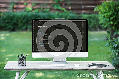 selective focus of computer monitor with programming language code at table Editorial Stock Photo