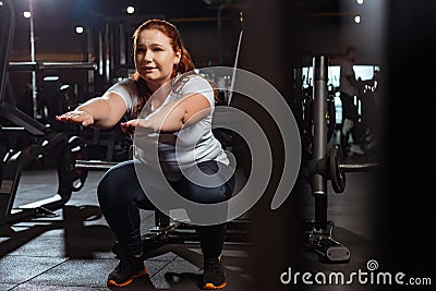 Focus of concentrated overweight squatting with outstretched hands Stock Photo