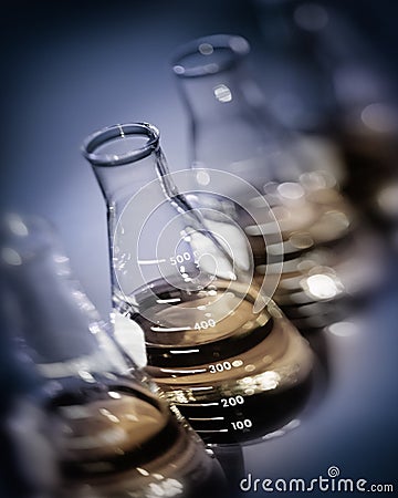 Selective focus laboratory flasks with yellow gold solutions Stock Photo