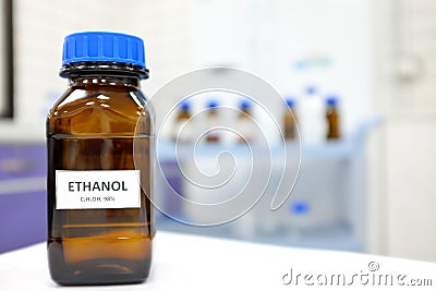 Selective focus of ethanol or ethyl alcohol brown amber glass bottle inside a laboratory. Blurred background with copy space. Stock Photo