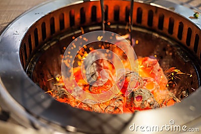 Selective focus on Glowing and Flaming hot natural wood charcoal lump in food restaurant BBQ grill stove background. Natural Heat Stock Photo