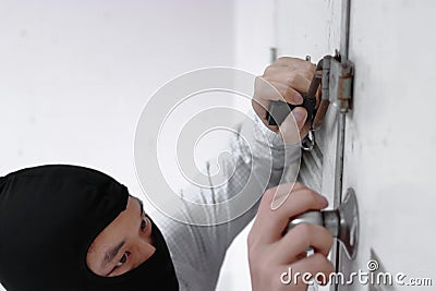 Selective focus on hands of masked thief in black balaclava trying to break into house Stock Photo