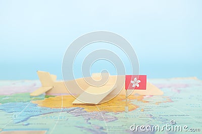 Selective focus of Hong Kong flag in blurry world map and wooden airplane model. Hong Kong as travel and tourism destination Stock Photo