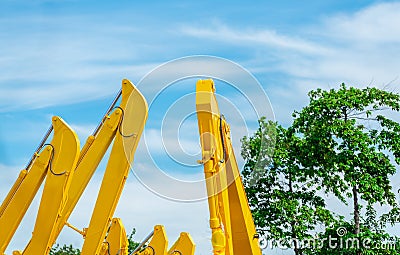 Selective focus on hydraulic piston arm of yellow backhoe on blur tree. Huge metal bulldozer. Excavator machine. Hydraulic Stock Photo
