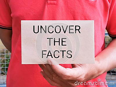 Hand holding envelope with text UNCOVER THE FACTS Stock Photo