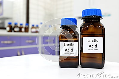 Selective focus of lactic acid liquid solution in dark brown glass bottle in a white chemistry laboratory background. Chemical Stock Photo