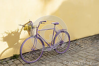 selective focus on lavender bicycle with flowers on yellow wall background Stock Photo