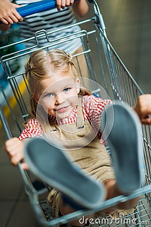 selective focus of little girl sitting in shopping cart Stock Photo