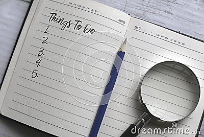 Selective focus of magnifying glass,pencil and notebook written with list of numbers of things to do Stock Photo