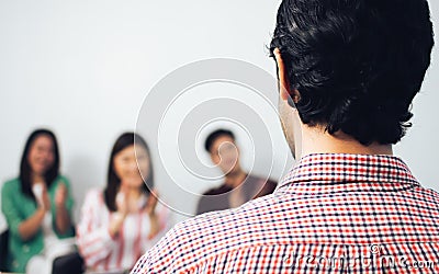 focus of man's back while teaching, training or coaching people in a room with blur background of happy persons clappin Stock Photo