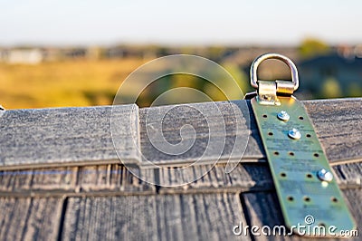 Selective focus on a metal temporary anchor installed on the peak of a roof for fall protection. Stock Photo