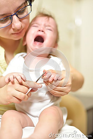 Selective focus The mother cuts the child`s toenails on the arm with baby safe scissors. Self care authentic concept. Mother care Stock Photo