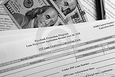 Selective focus photo of paycheck protection program loan forgiveness application form revised, on a background of dollar bills Stock Photo