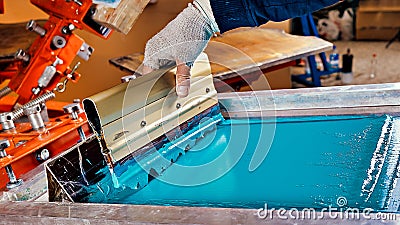 Selective focus photo of print screening apparatus and a worker. serigraphy production. printing images on t-shirts Stock Photo