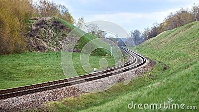Selective focus railway track twists and turns between hills. Empty rounding and turning single track of railways Stock Photo