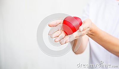 Selective focus of red heart held by female nurse`s both hand, representing giving all effort to deliver high quality service mind Stock Photo