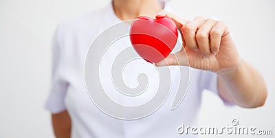 Selective focus of red heart held by female nurse`s hand, representing giving all effort to deliver high quality service mind Stock Photo