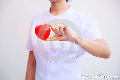 Selective focus of red smiling heart held by female nurse`s hand, representing giving effort high quality service mind to patient. Stock Photo