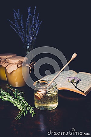 selective focus of rosemary and honey stick in jar with honey on black Stock Photo