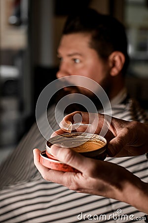 Selective focus on round jar with hair gel for styling in male hands. Stock Photo