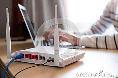 Selective focus at router. Internet router on working table with blurred man connect the cable at the background. Fast and high Stock Photo