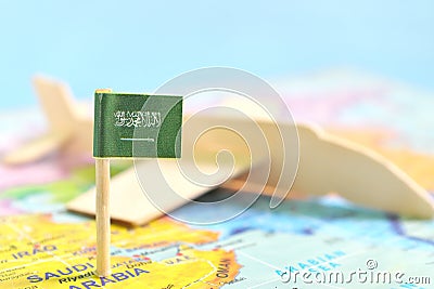 Selective focus of Saudi Arabia flag in blurry world map and airplane model. Travel and tourism destination concept. Stock Photo