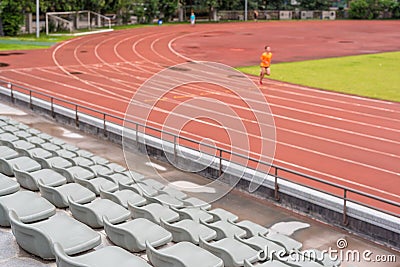 Selective focus on seats in a stadium with a man running Stock Photo