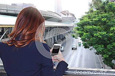 Selective focus and shallow depth of field. Back view of woman taking a photo of traffic car in city with mobile smart phone Stock Photo