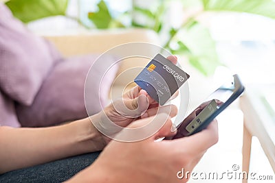 Selective focus shot at credit card mock up. Asian men hand holding credit card while type information into mobile smartphone Stock Photo
