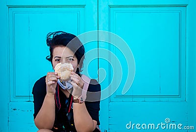 Selective focus shot of a female traveler in a mask holding a donut Stock Photo