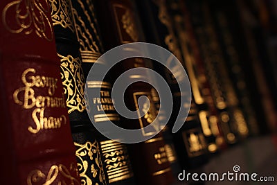 Selective focus shot of gold lettering on antique book covers on a bookshelf Editorial Stock Photo